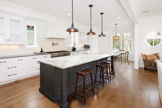 a large kitchen with an island in the middle and two bar stools at the end