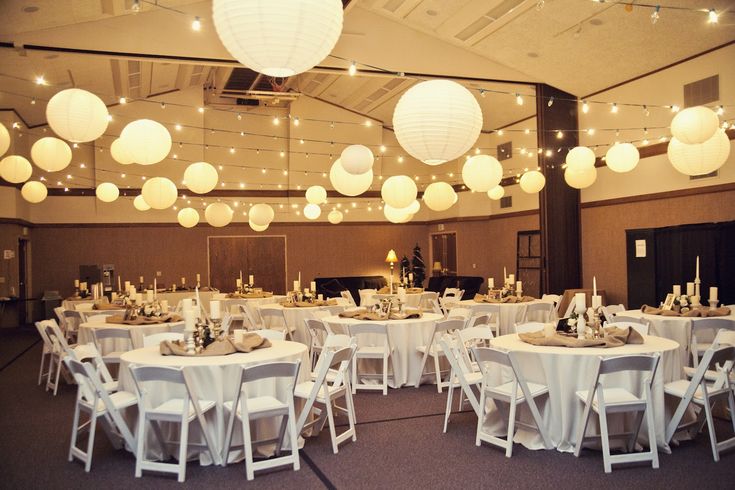 a banquet hall with tables and chairs covered in white paper lanterns