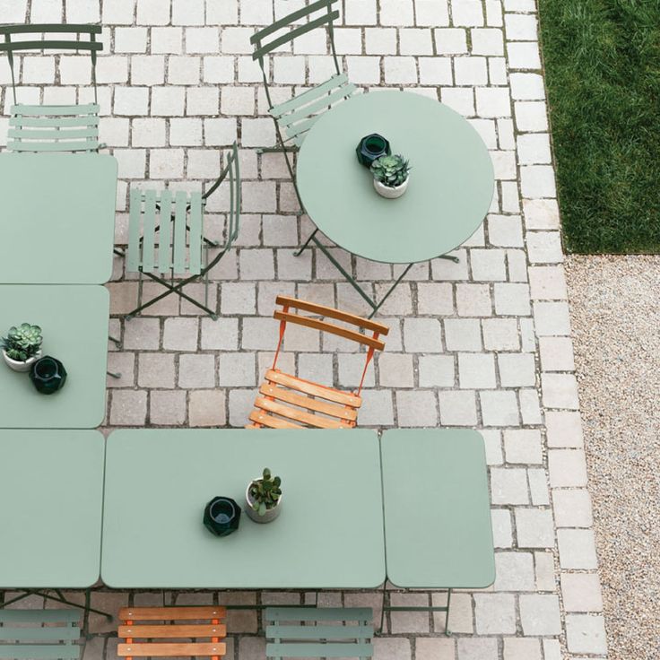 an overhead view of a table and chairs on a brick patio with potted plants