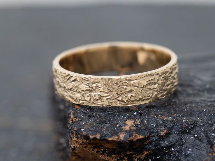 a gold wedding ring sitting on top of a rock