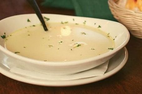 a white bowl filled with soup sitting on top of a table next to a basket of bread