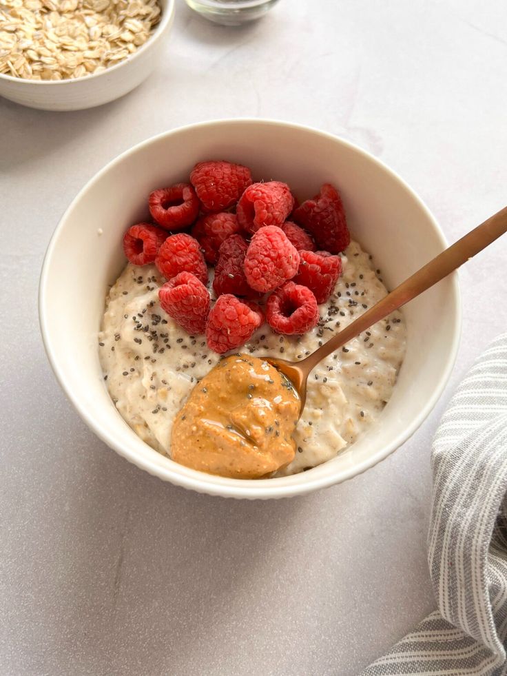 a bowl filled with oatmeal and raspberries next to a spoon