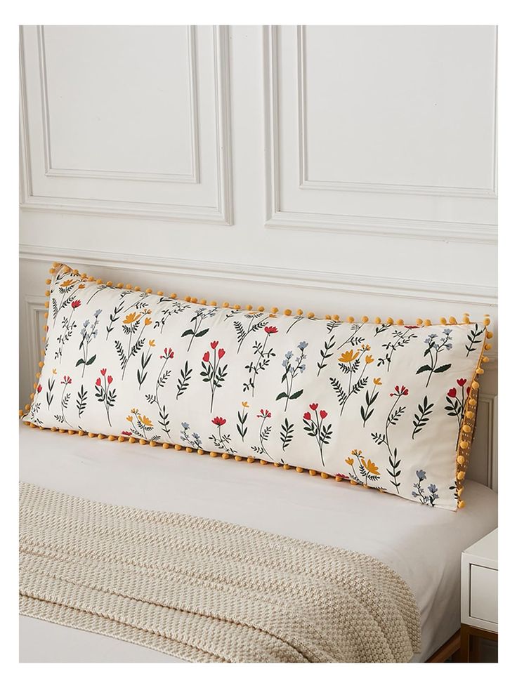 a white bed topped with a pillow covered in flowers