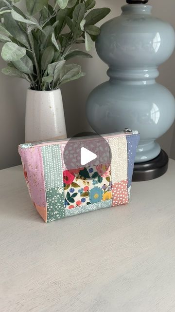 a small purse sitting on top of a table next to a vase with a plant