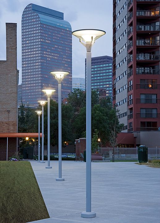 a couple of street lamps sitting on top of a cement ground next to tall buildings