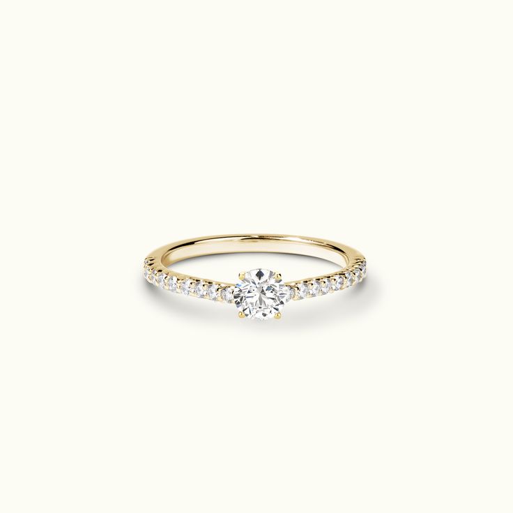 a yellow gold engagement ring with diamonds on the band and a single diamond in the center