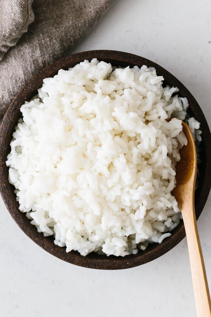 white rice in a bowl with a wooden spoon