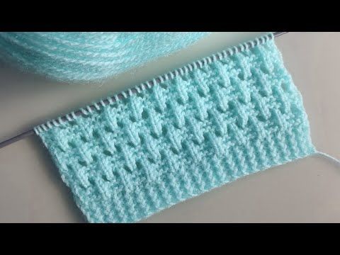 a close up of a knitted piece of cloth next to a knitting needle on a table