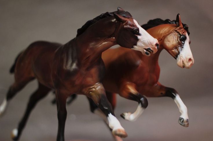 two toy horses are running side by side