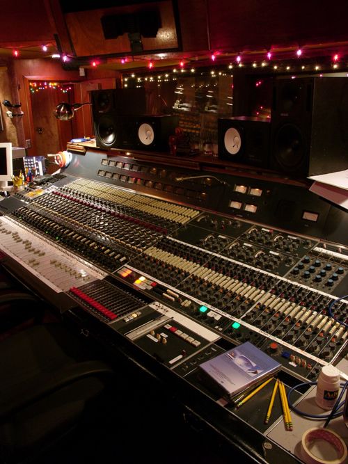 a recording studio with sound board, mixing equipment and lights on the wall behind it