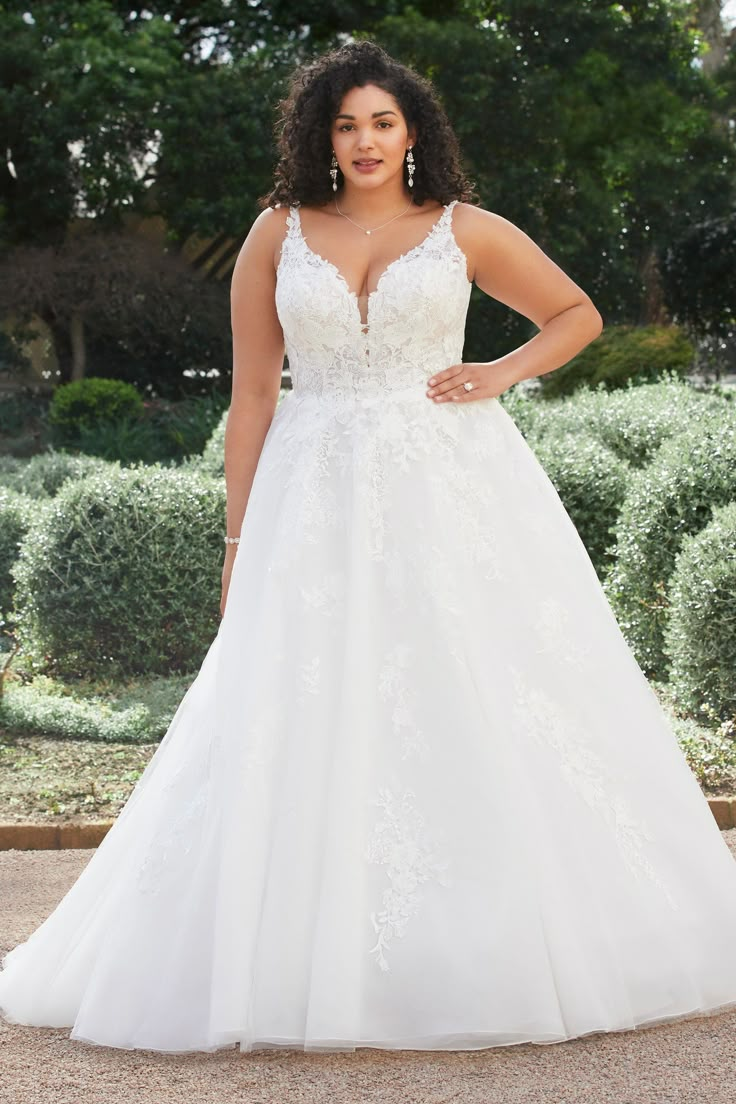 a woman in a wedding dress posing for the camera with her hands on her hips