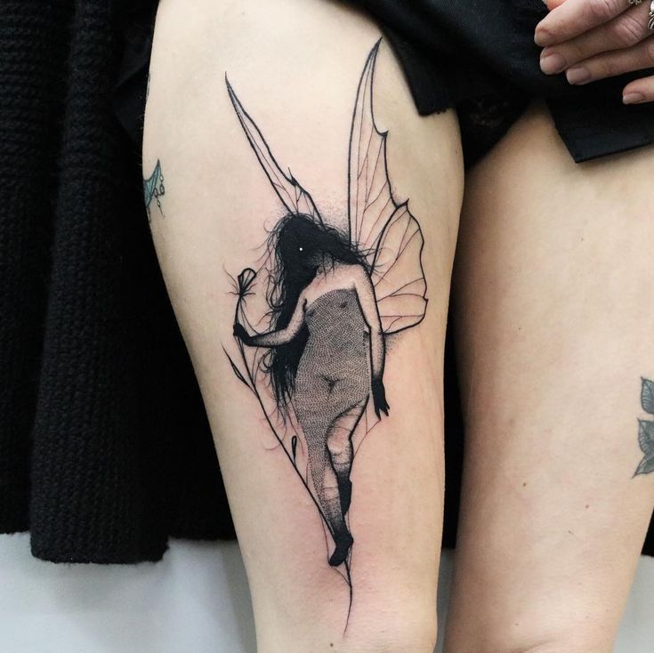 a woman's thigh with a fairy tattoo on her leg and the bottom half of her legs