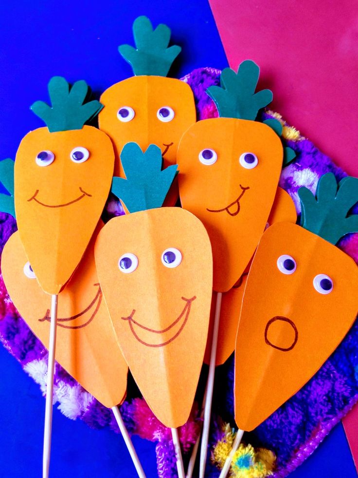 paper carrots with faces on them sitting on a table