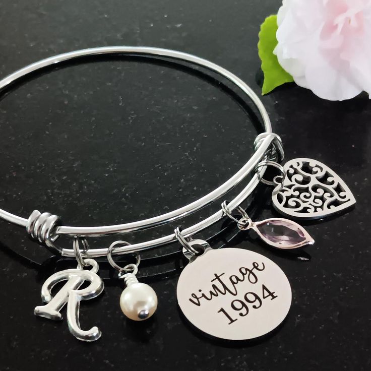 a close up of a bracelet on a table with flowers and a flower in the background