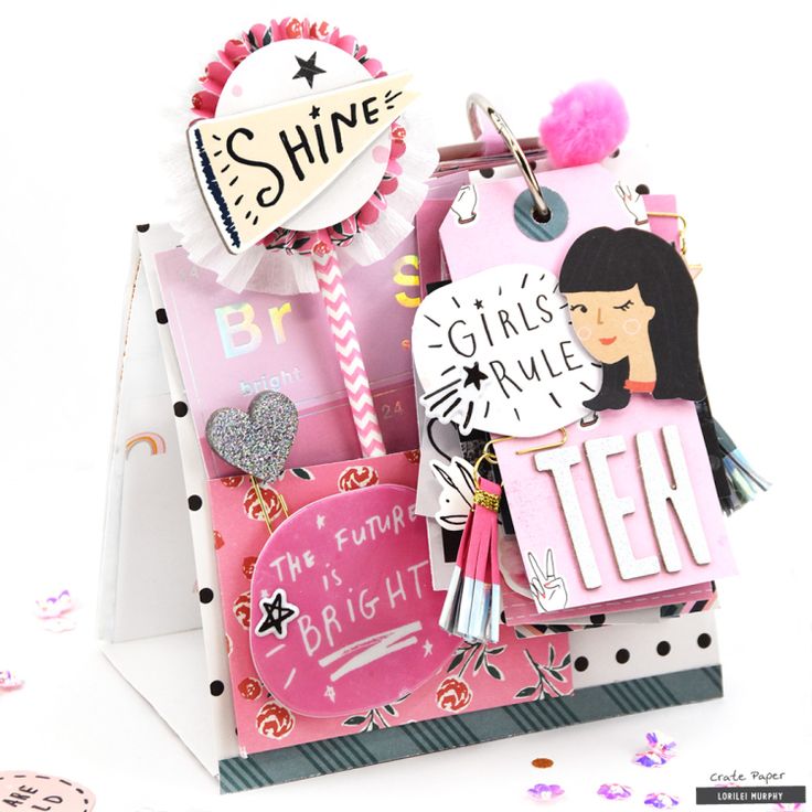 a pink and white gift bag filled with lots of different types of items on top of it