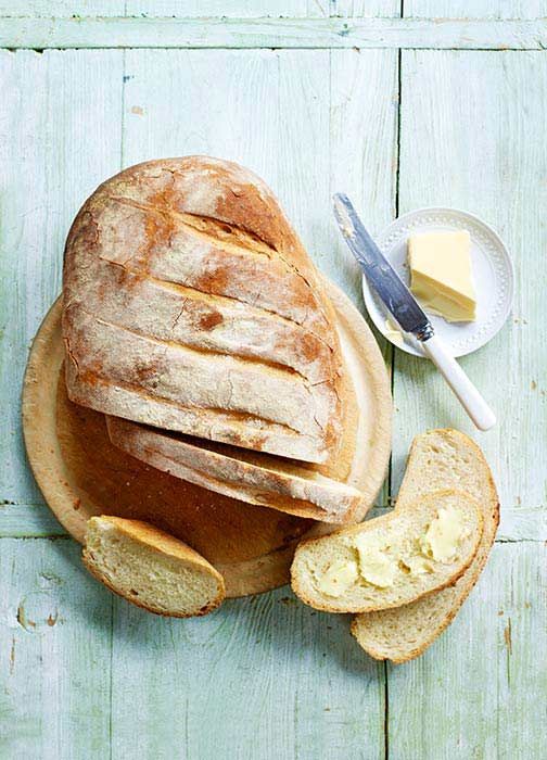 a loaf of bread sitting on top of a cutting board next to slices of bread