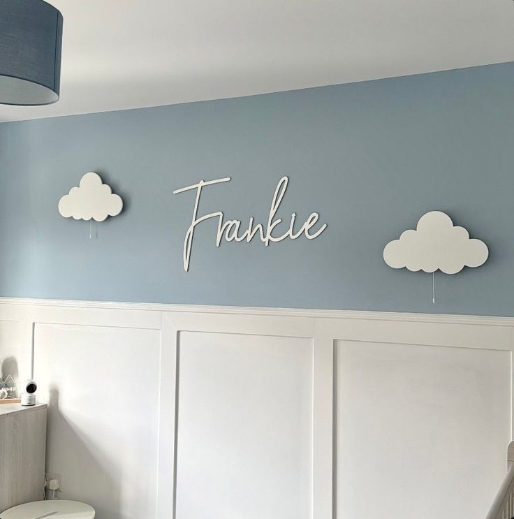 a white toilet sitting in a bathroom next to a wall with name cutouts on it