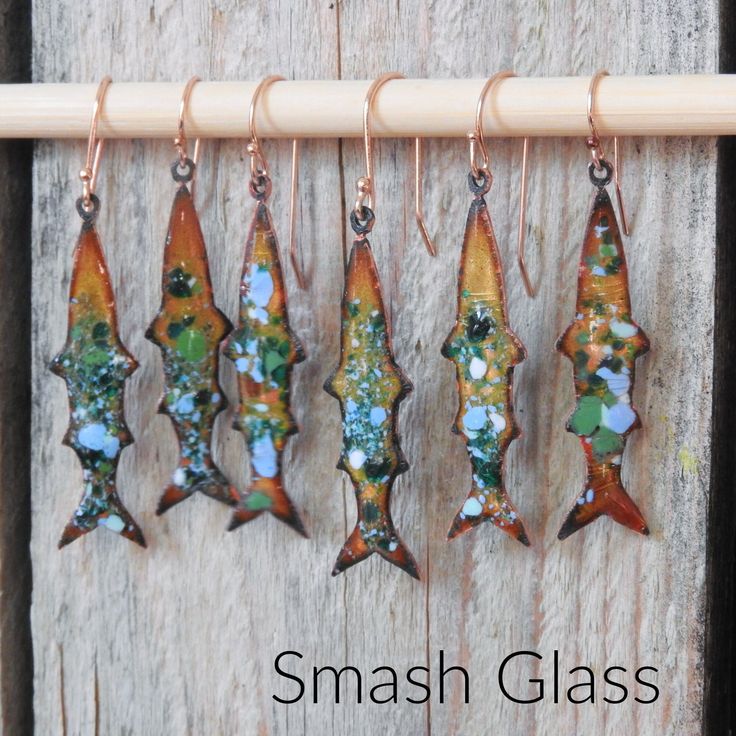 five glass fish hanging from hooks on a wooden board with the words smash glass written below them