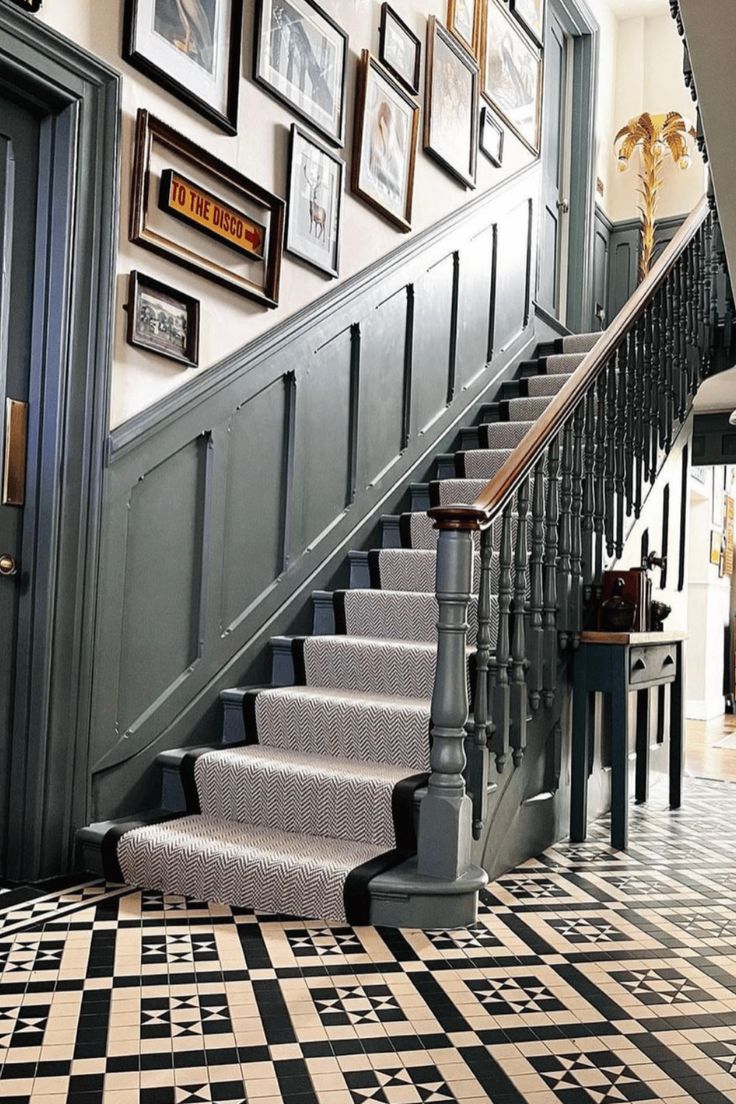 a staircase with pictures on the wall and carpeted flooring in front of it