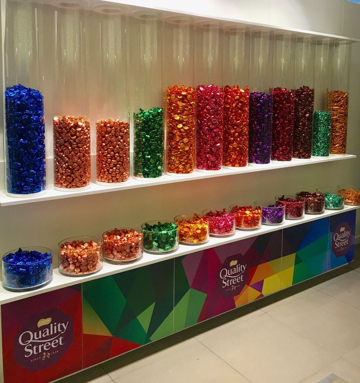 there are many different colored candies on the shelf