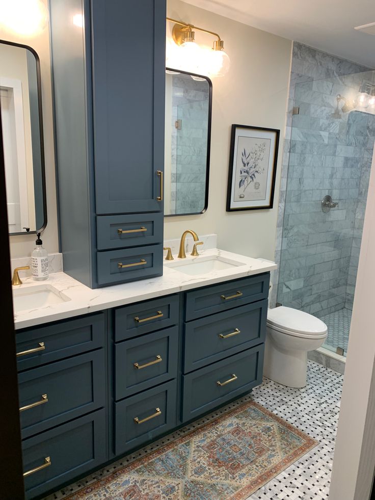 a bathroom with blue cabinets and a white toilet next to a walk - in shower