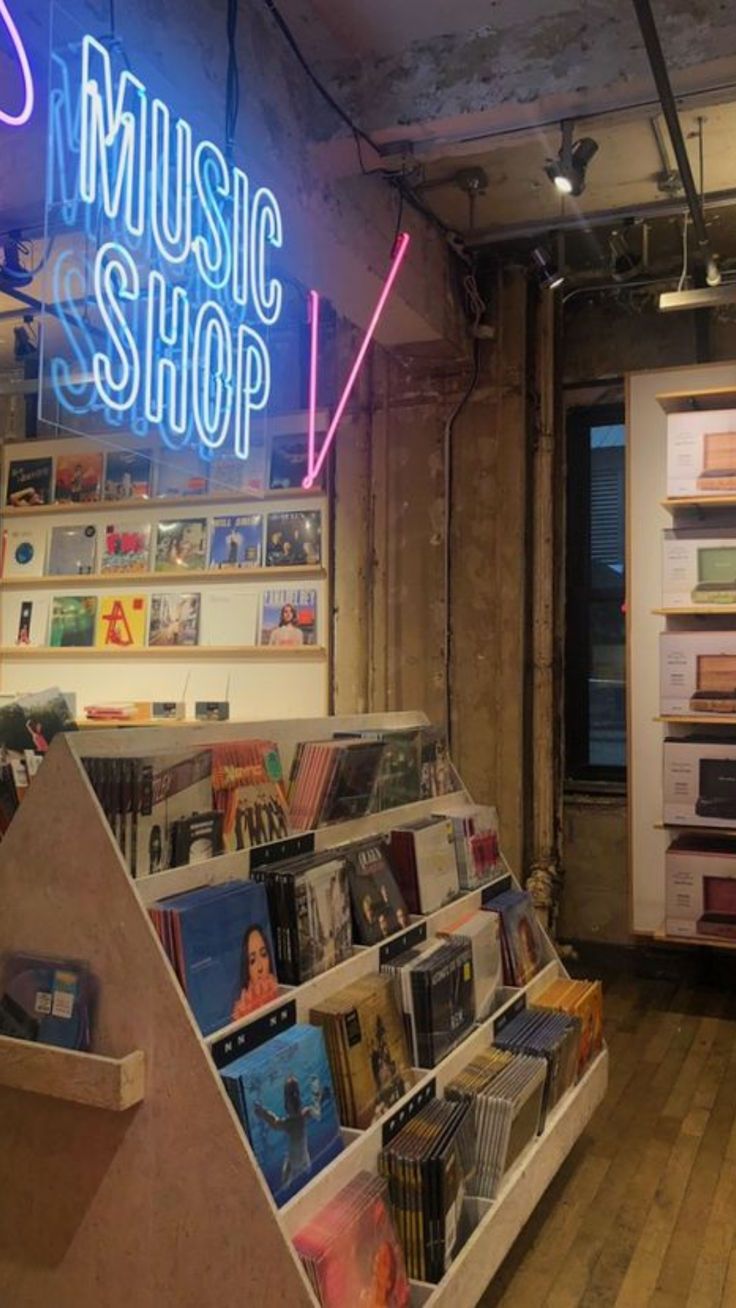 the inside of a music shop with various records on shelves and neon signs above it