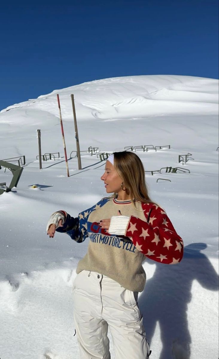 a woman is standing in the snow wearing skis and holding onto her mitt