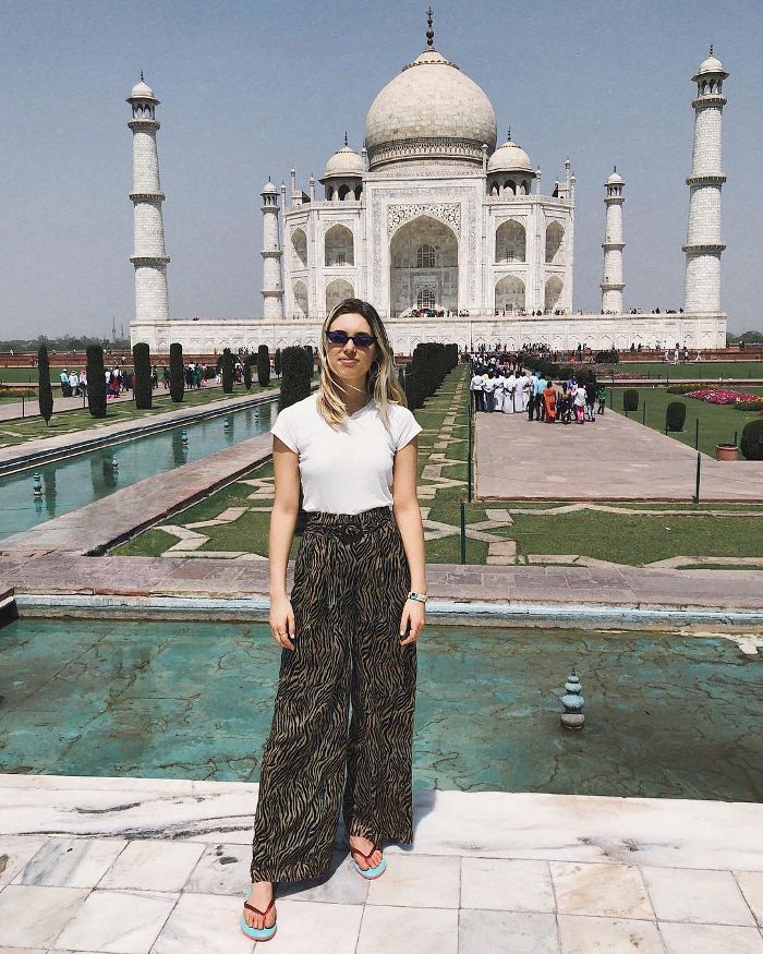 a woman standing in front of the tajwa, india monument with her hands on her hips