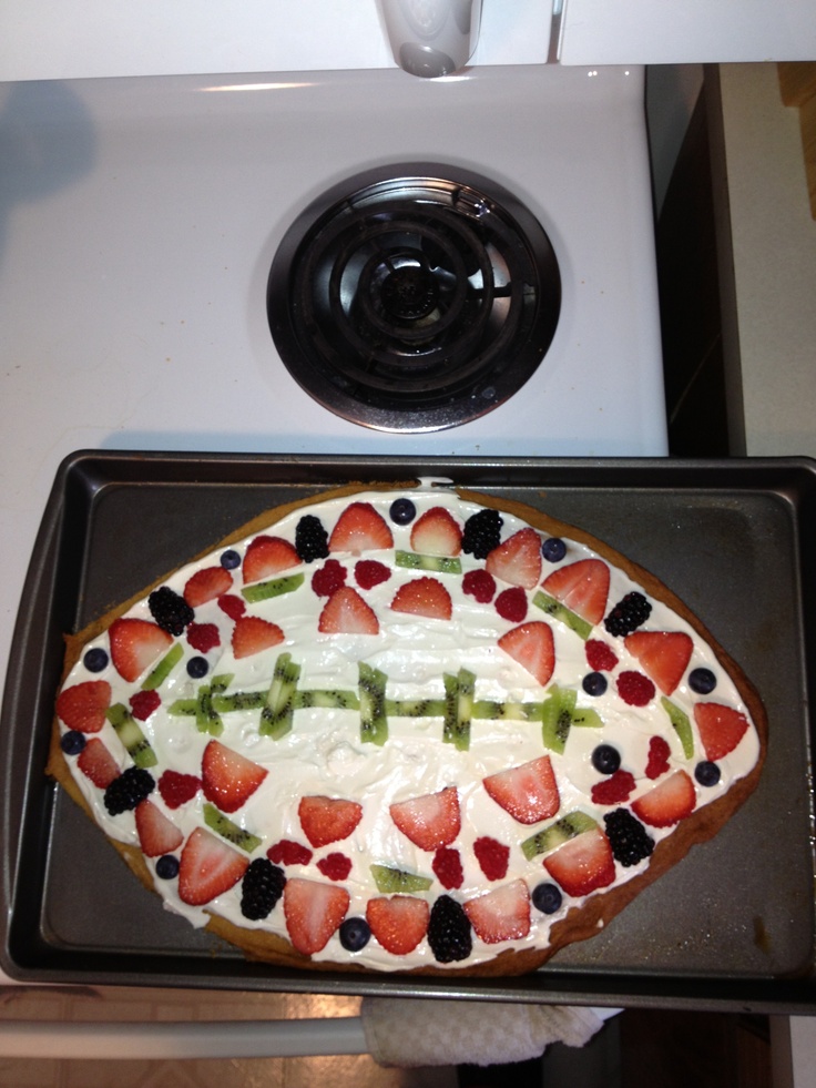 a cake with strawberries and blackberries in the shape of a football on it