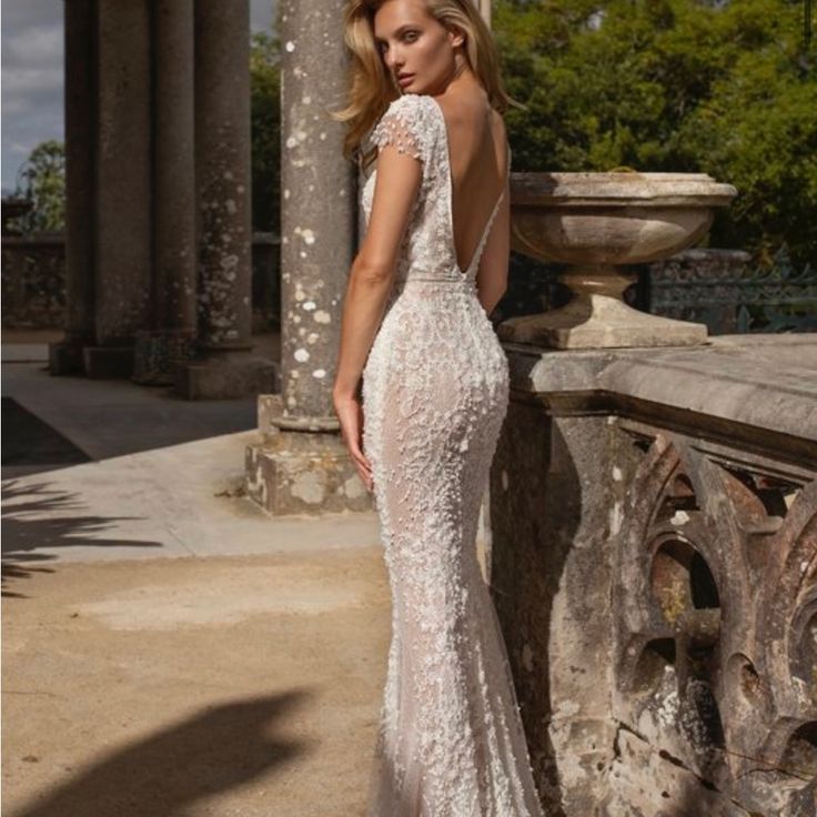 a woman in a white wedding dress standing on a stone wall with columns and pillars behind her