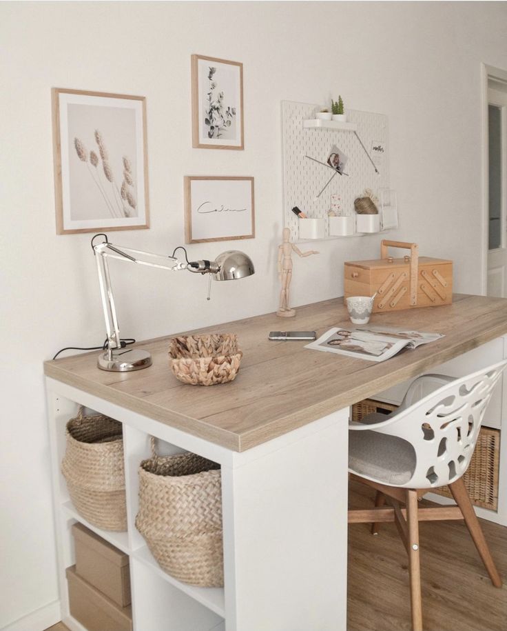 a desk with some baskets and pictures on the wall above it in a home office