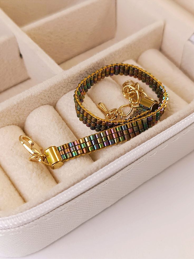 an open white box containing two bracelets and a gold - plated clasp on it