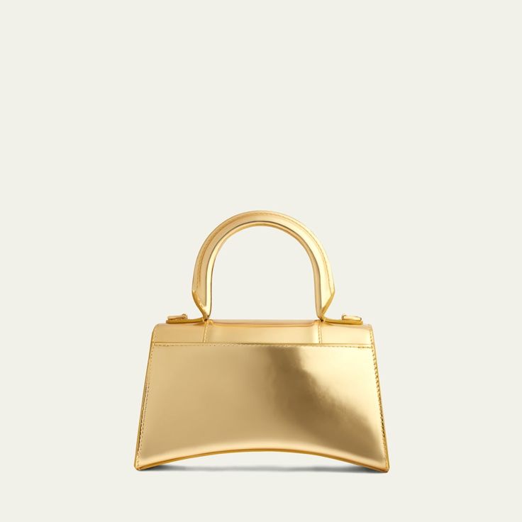 Balenciaga "Hourglass" satchel in mirror calfskin leather. Rolled top handle. Removable, adjustable shoulder strap. Flap top with hanging "B" hardware; snap closure. Exterior, slip compartment at back. Interior, one slip pocket. Approx. 5.1"H x 7.5"W x 3.2"D. Spot clean. Made in Italy. Designer Flap Bag With Handles For Evening, Modern Evening Flap Bag With Handles, Luxury Handheld Flap Bag With Gold-tone Hardware, Modern Flap Bag With Top Handle, Luxury Gold Flap Bag For Shopping, High-end Flap Bag With Top Carry Handle For Evening, High-end Gold Bag With Top Carry Handle, Designer Evening Flap Bag With Double Handle, High-end Gold Bags With Top Carry Handle