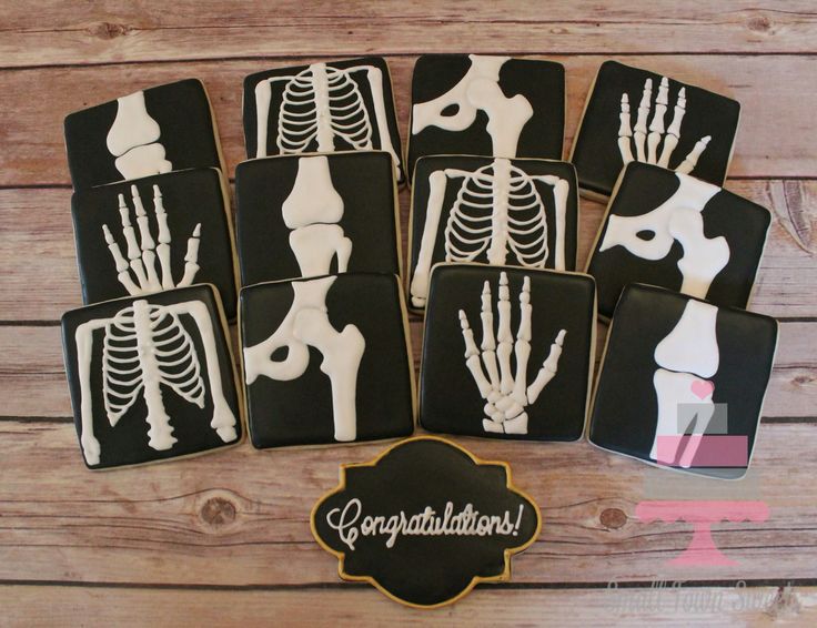 decorated cookies in the shape of skeleton's bones on a wooden table with a sign that says congratulations