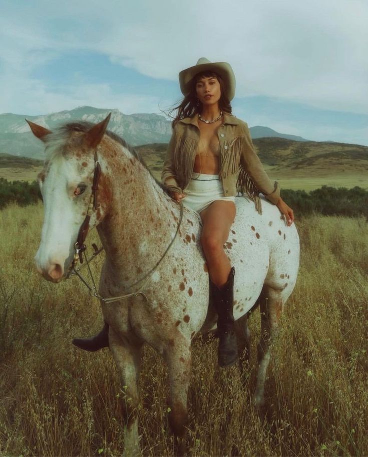 a woman sitting on top of a horse in a field