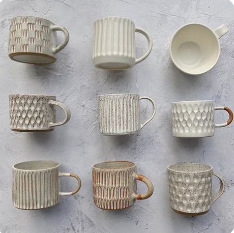 nine white cups and saucers lined up on a gray surface with one cup in the middle