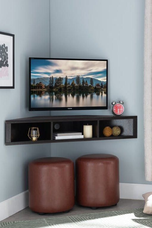 a flat screen tv sitting on top of a wooden shelf next to two brown stools