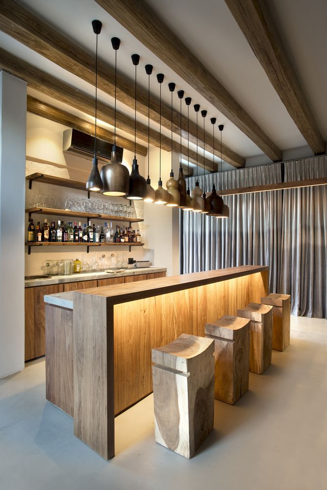 a bar with stools and lights hanging from the ceiling in a room filled with windows