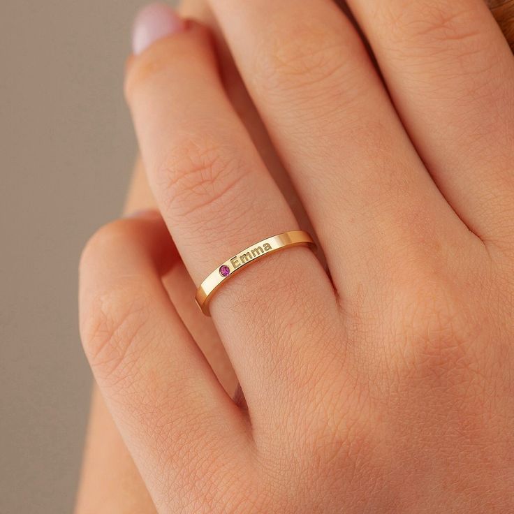 a woman's hand wearing a gold ring with an amethoraite stone