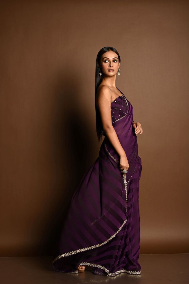 Indulge in luxurious elegance with our Dark Purple Self-Striped Georgette Saree, adorned with a stunning Swarovski and Cut Dana embroidery border. This exquisite saree combines rich color with intricate detailing, making it the perfect choice for any special occasion. Festive Purple Saree With Embroidered Border, Embellished Purple Georgette Pre-draped Saree, Purple Georgette Saree, Purple Embroidered Georgette Pre-draped Saree, Luxury Embroidered Purple Pre-draped Saree, Luxury Purple Saree With Border, Baluchari Saree, Golden Blouse, Silver Blouse