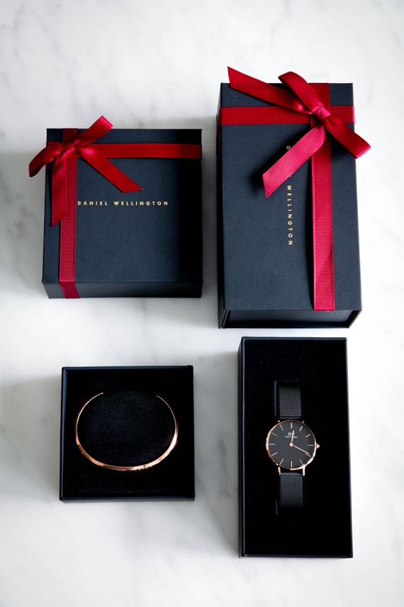 three black boxes with red ribbon and a watch