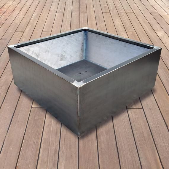 a square metal box sitting on top of a wooden floor in front of a building