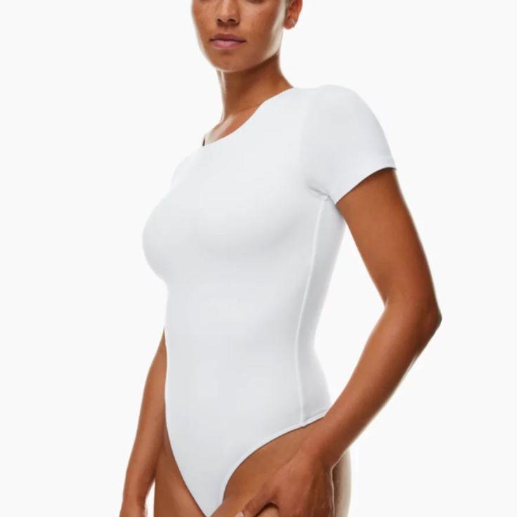 a woman in a white bodysuit posing for the camera with her hands on her hips