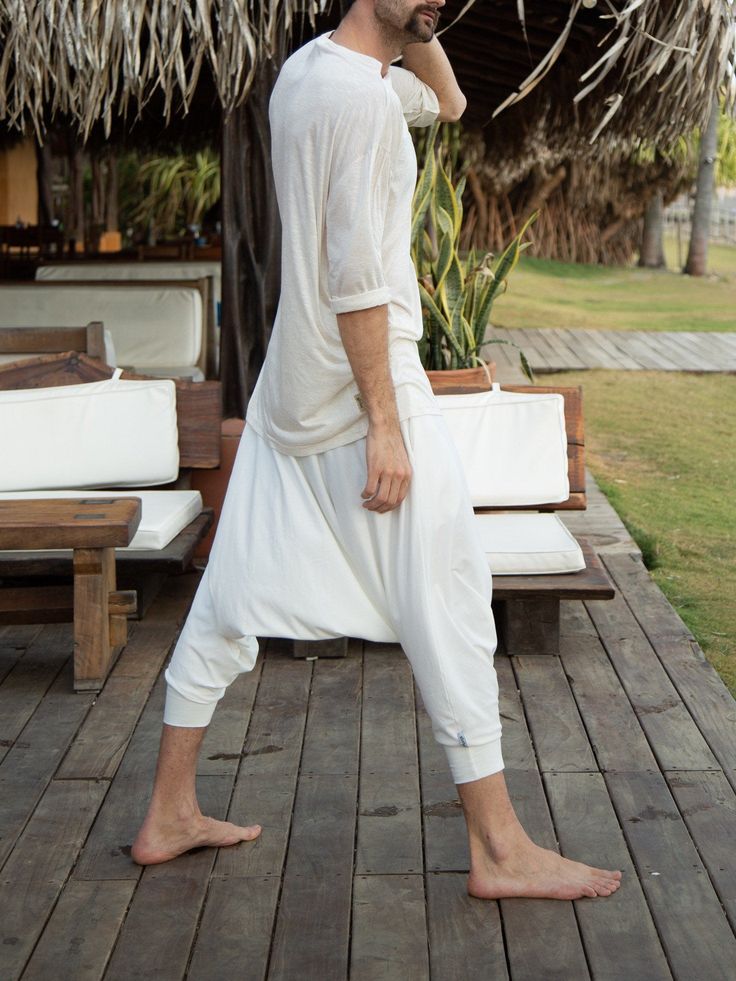 This super comfy ivory white loose top is a great option for your favorite lounge wear, or a yoga or meditation shirt. It has a nice edgy urban look and it can be worn in the city, as a part of a sound bath or a Ceremony journey, or as a nice Jedi or Nomad style festival outfit. Try it with our glorka harem pants - they go so well together! Materials: stretch cotton jersey. Fabric for this pair was bought in Fashion District in LA and the pant was handmade in one of our Manhattan studios in NYC. Casual White Top For Meditation, White Relaxed Fit Top For Yoga, Casual White Yoga Tops, White Harem Pants For Loungewear, Cotton Relaxed Fit Top For Meditation, White Relaxed Fit Yoga Top, White Flowy Shirt Men, White Organic Cotton T-shirt For Loungewear, Bohemian Lounge