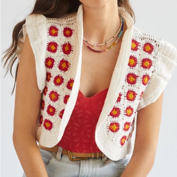 a woman wearing a red top and white cardigan with flowers on the back, standing in front of a white background