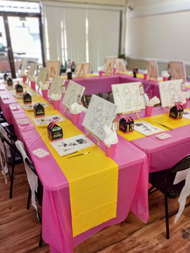 there are many tables set up with pink and yellow table cloths on the tables