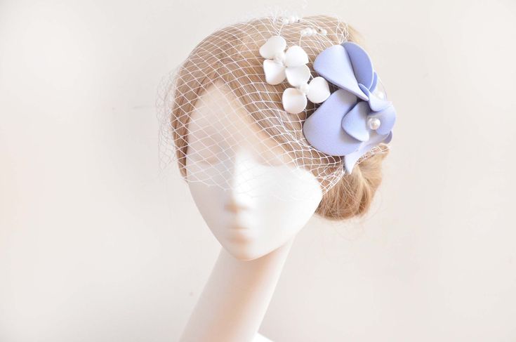 a white mannequin head wearing a veil with blue and white flowers on it