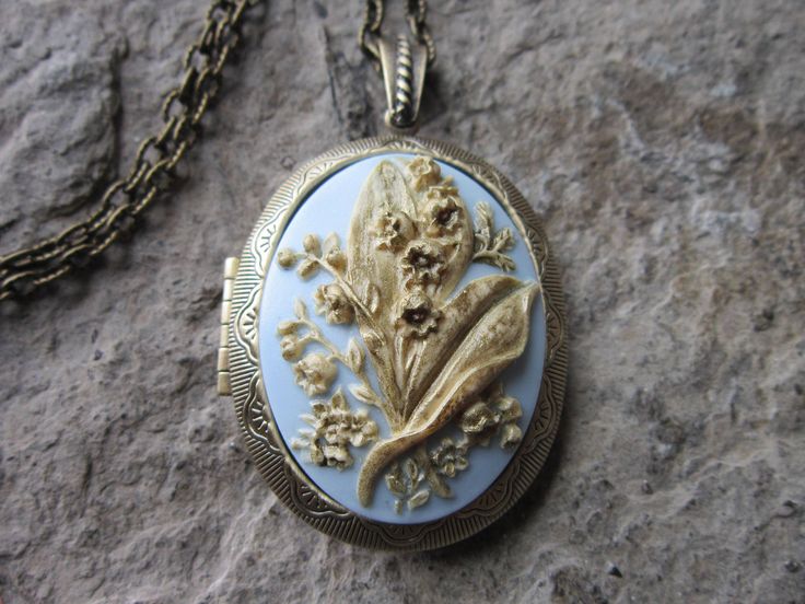 "Beautiful cameo locket, choose bronze, antiqued silver, or silver (other colors and styles are available in my shop so please do browse The cameo is a gorgeous lily of the valley. Stunning colors, each cameo is individually hand painted and antiqued, each an original The bronze and silver plated lockets are Victorian style with beautiful scroll on both the front and back about 2\" long, please see the photos. They can hold two photos, a treasured keepsake or both. Pass down from generation to g Antique Brass Locket Necklace For Wedding, Antique Finish Brass Locket Necklace For Wedding, Bronze Brass Locket Necklace For Wedding, Bronze Vintage Charm Jewelry For Wedding, Bronze Locket Necklace With Vintage Charm For Wedding, Bronze Antique Finish Jewelry For Wedding, Bronze Antique Finish Wedding Jewelry, Elegant Bronze Locket Necklace For Wedding, Bronze Heirloom Jewelry For Wedding