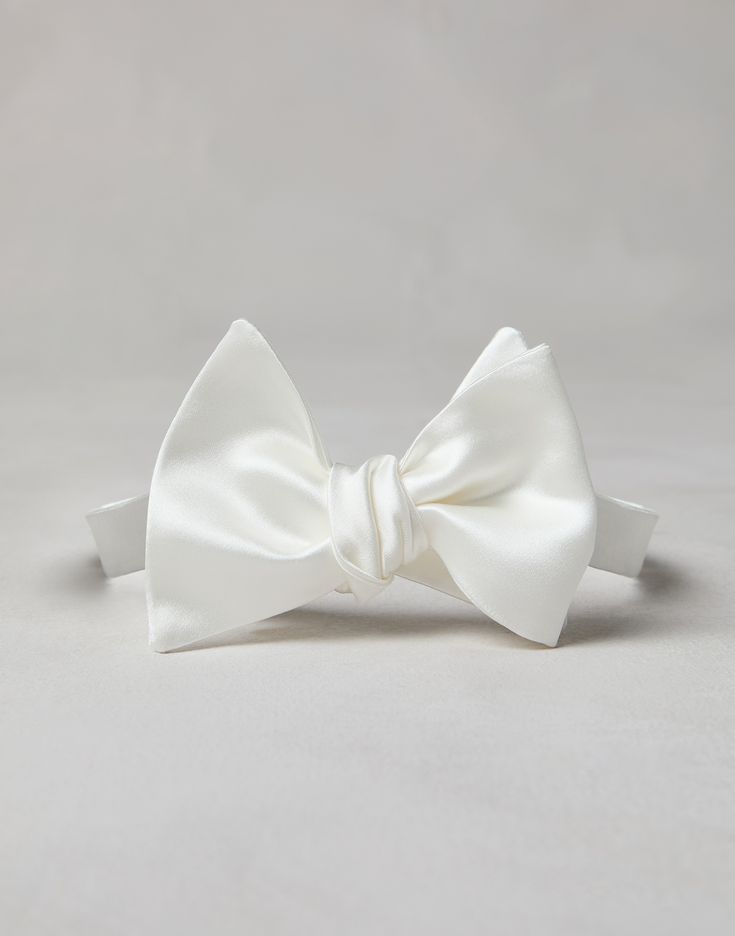 Cotton and silk satin bow tie An essential accessory for evening events, the cotton and silk satin bow tie completes tuxedos with classic flair. This accessory, which must be tied, is adjustable thanks to a convenient hook-and-loop closure behind the neck. Classic Pre-tied Satin Bow Tie, Classic Pre-tied Decorative Bow, Classic Adjustable Satin Bow Tie, Elegant White Bow Tie For Black-tie Events, Classic White Adjustable Bow Tie, Classic Pre-tied Satin Bow, Classic Pre-tied Tie With Decorative Bow, Classic Adjustable Bow With Detachable Feature, White Bow Tie For Formal Occasions