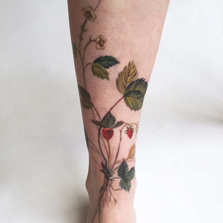 a woman's foot with tattoos on it and flowers growing out of the plant